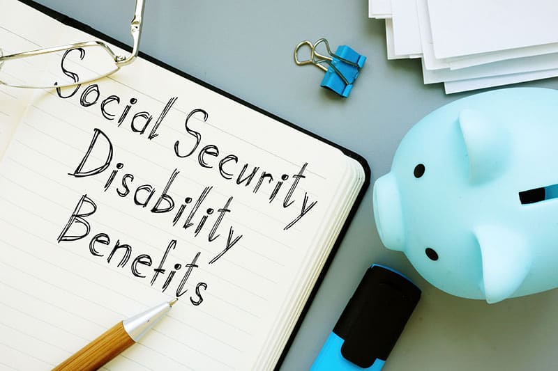 A piggy bank and notepad to Increase Approval Chances For Disability Benefits.