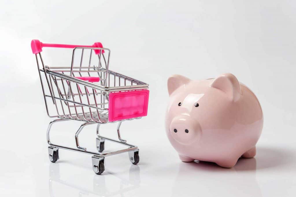 A piggy bank near a shopping cart as a strategy to save money on groceries.