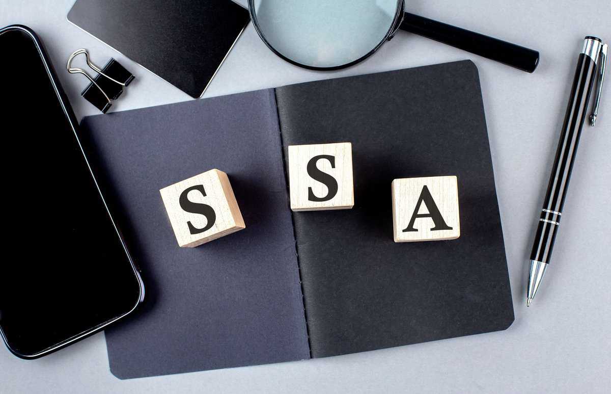 a notepad with scrabble blocks spelling the word sasa next to a, utilized by someone receiving SSA benefits.