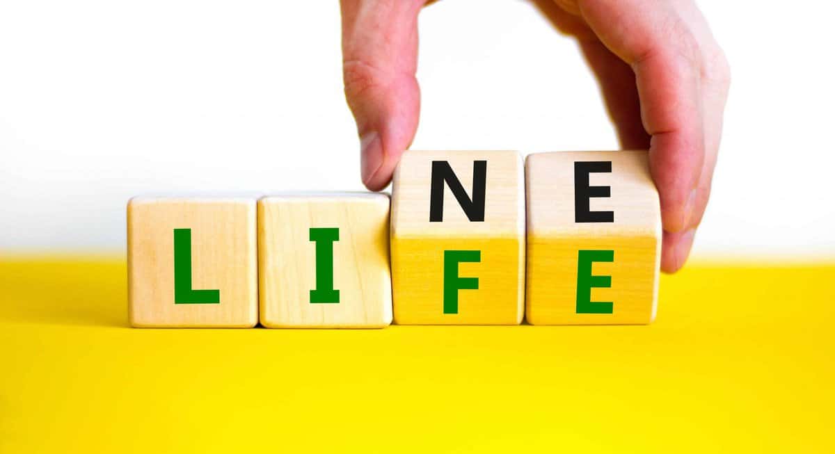 A hand is pushing a block with the word life on it, showing how people benefit from Lifeline.