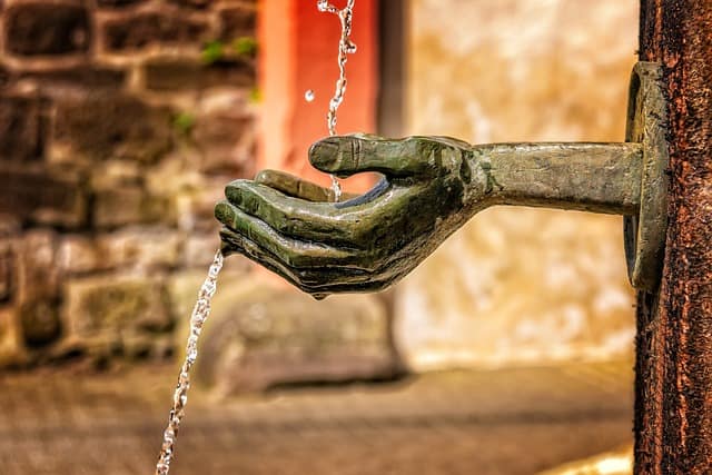 A hand is pouring water from a fountain at Camp Lejeune, known for its contaminated water.