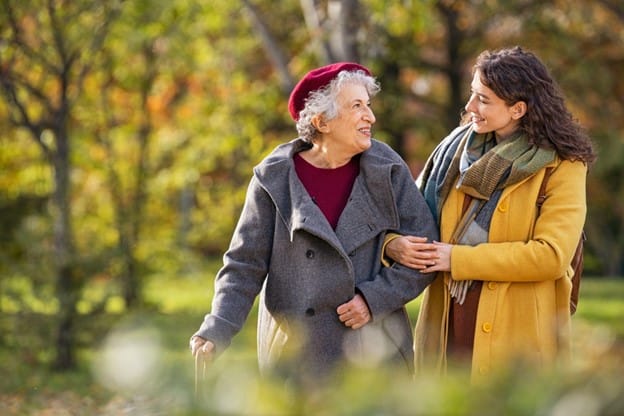 Two elderly women walking together in the park.