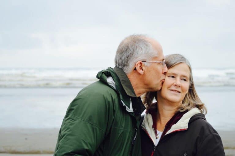An older couple kissing on the beach