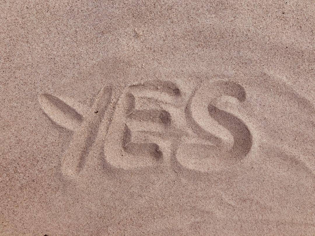 The word yes is written in the sand.